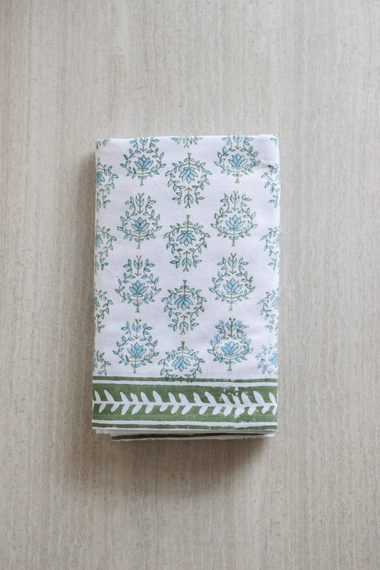 Folded table throw with sage and blue floral motifs and a sage leaf-patterned border