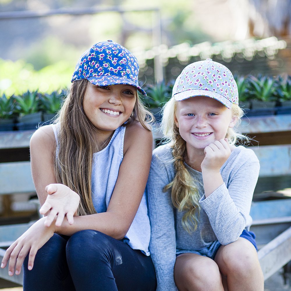 Two girls wearing floral baseball caps, one blue and one light blue.