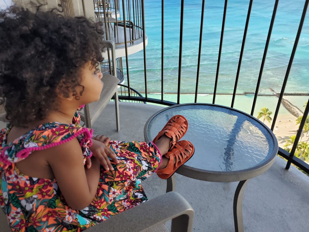 Orange barefoot sandals worn by child, open-toe design with ankle hook-and-loop