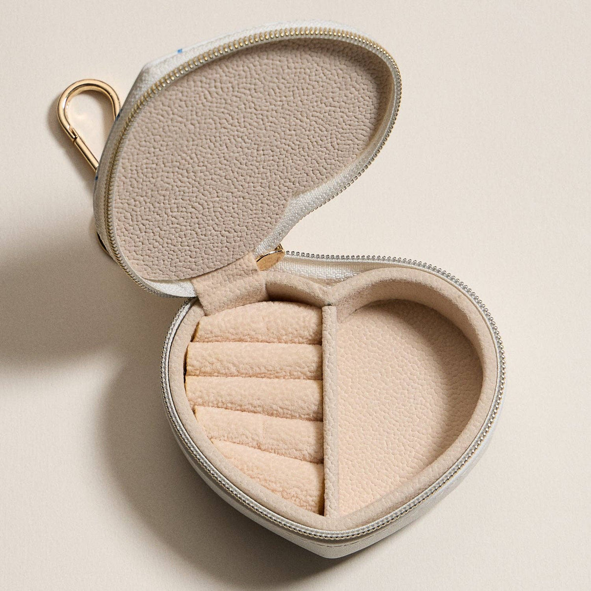 Heart-shaped jewelry travel case open with beige interior compartments