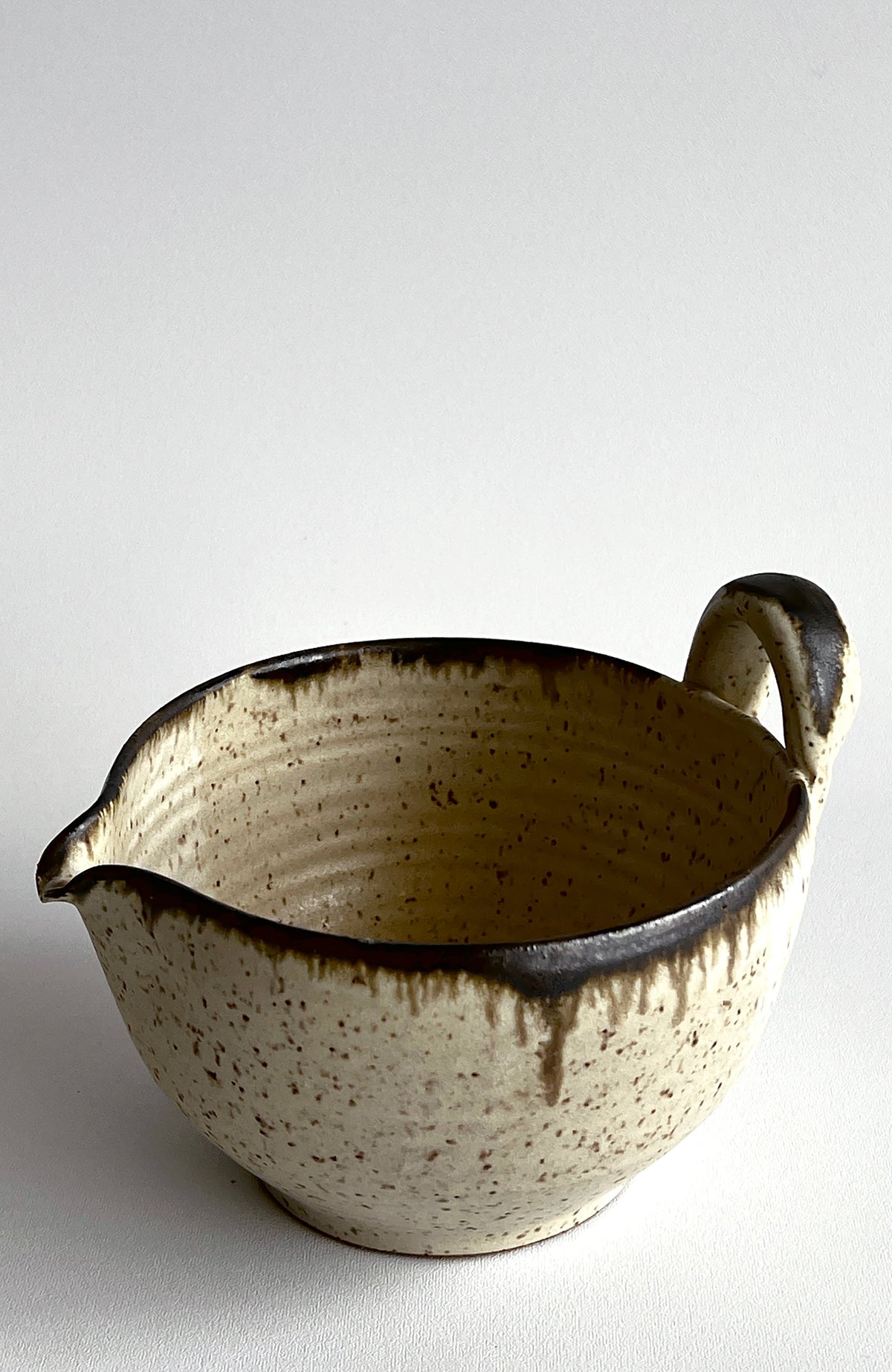 Speckled cream batter bowl with dark drip glaze and loop side handle