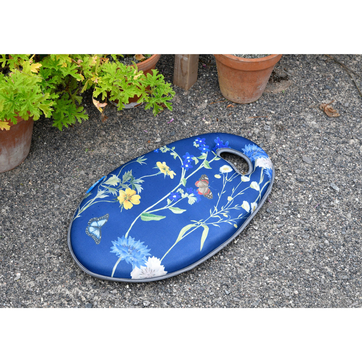 Blue garden kneeler pad with meadow floral print, oval form, and handle opening