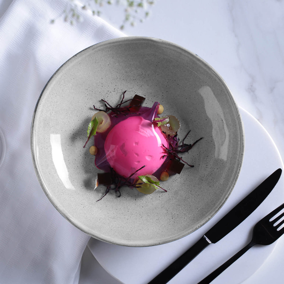 Grey speckled pasta plate with pink beet garnish, shallow round serving bowl.