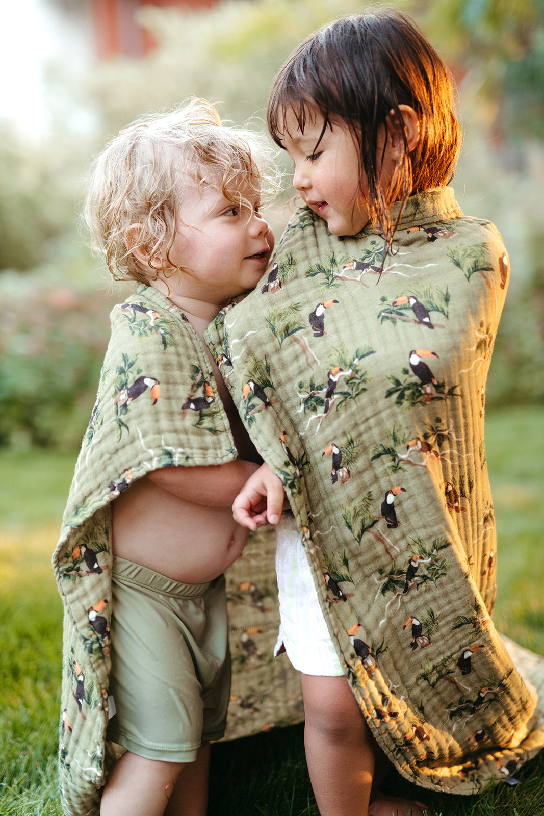 Tulip beach towel draped over children, light green with multicolor tulip print
