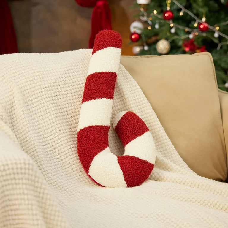Candy cane plush pillow in red-and-white stripes on a knitted throw