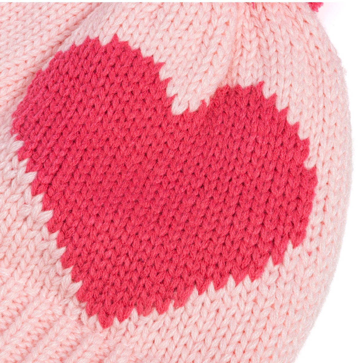 Close-up of a knitted pink heart motif on a pale pink winter hat
