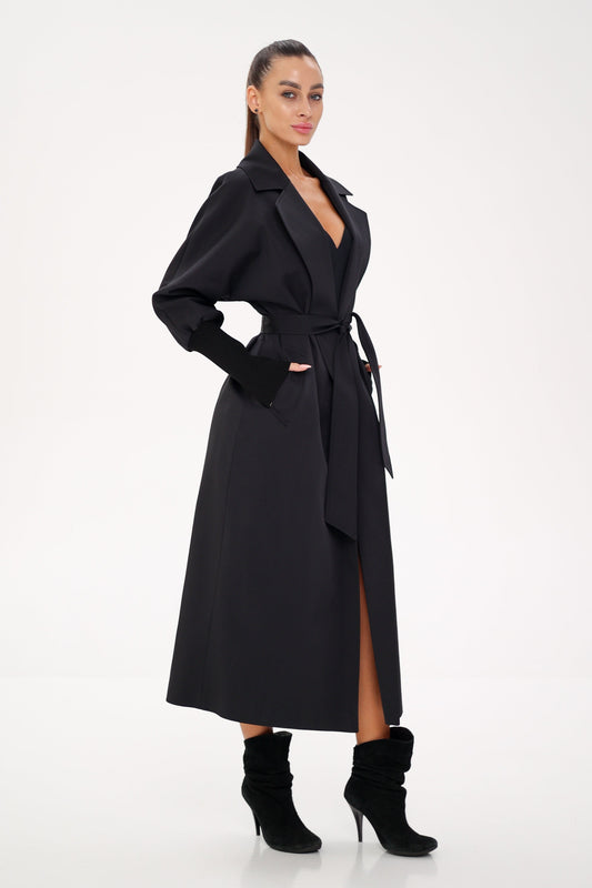 Black belted trench coat shown from the side, with a long split front