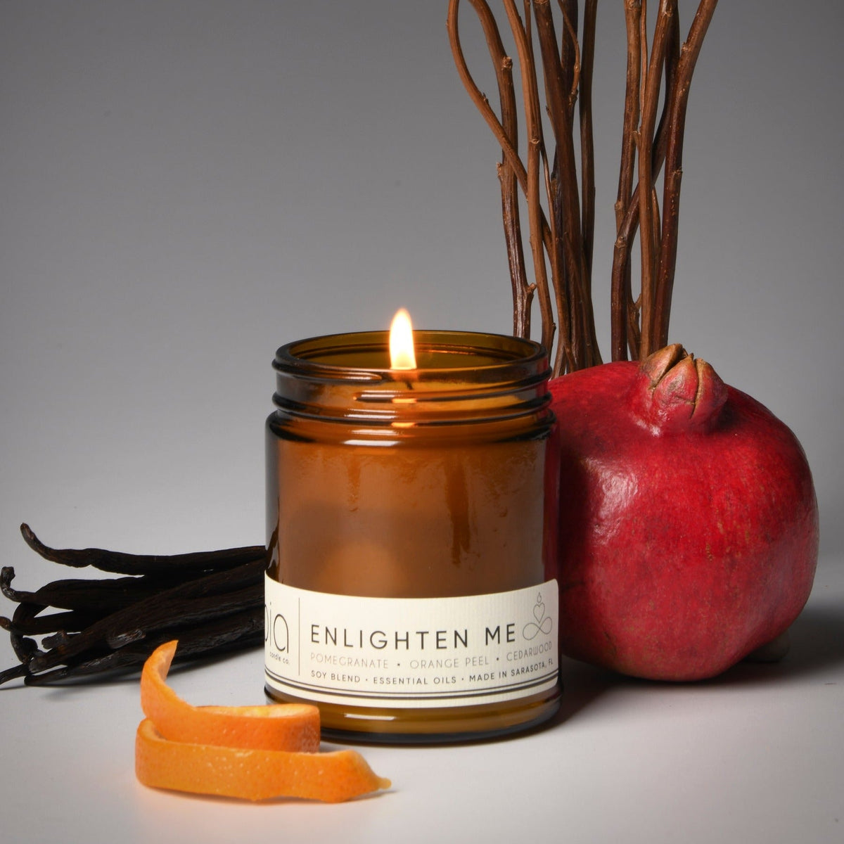 Amber glass jar candle with flame and white ENLIGHTEN ME label