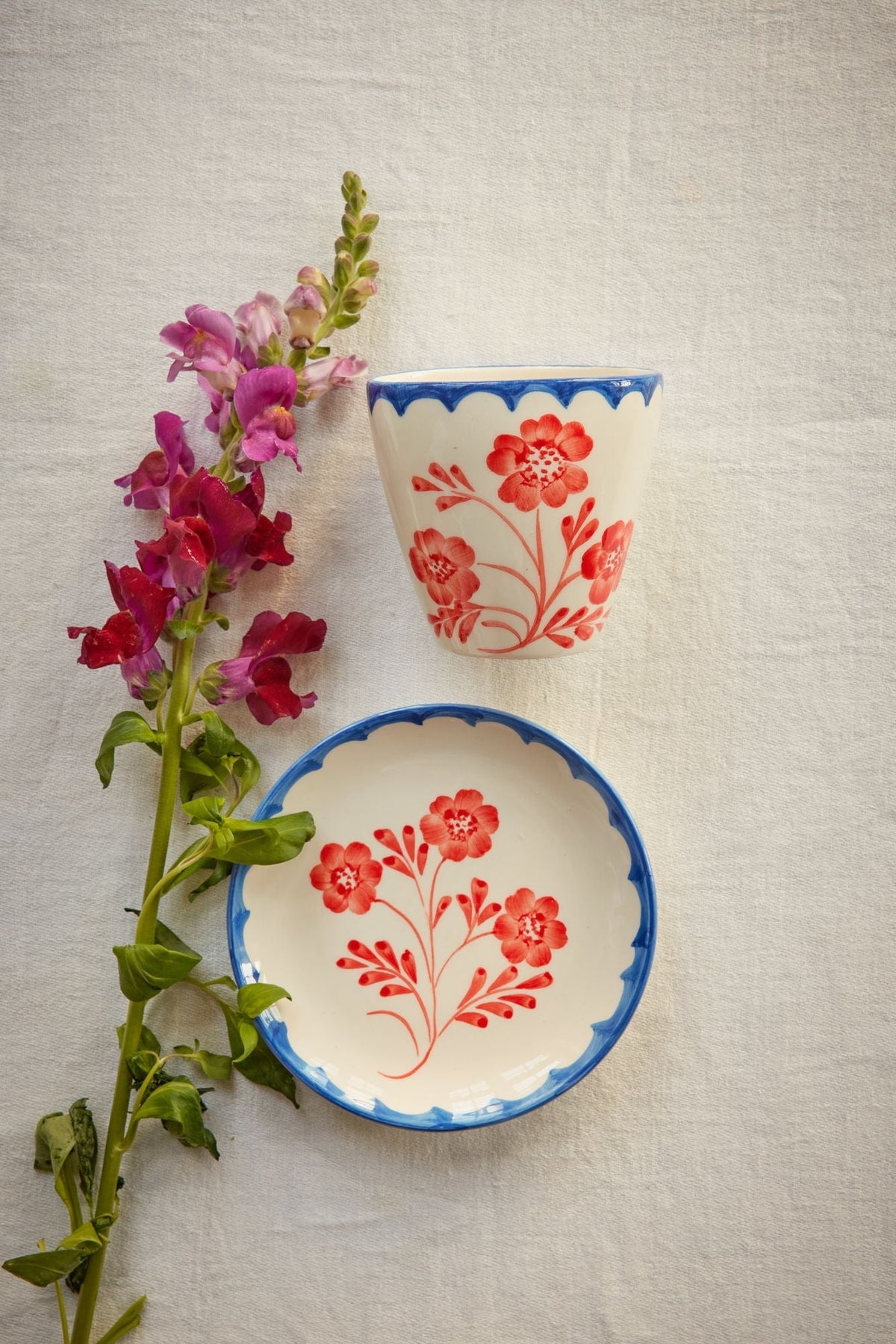 Ceramic oval cup with blue rim, red floral design, and matching oval saucer