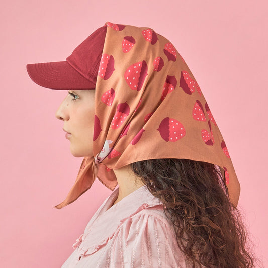 Tan bandana worn as a headscarf, with strawberry pattern and rabbit graphic.