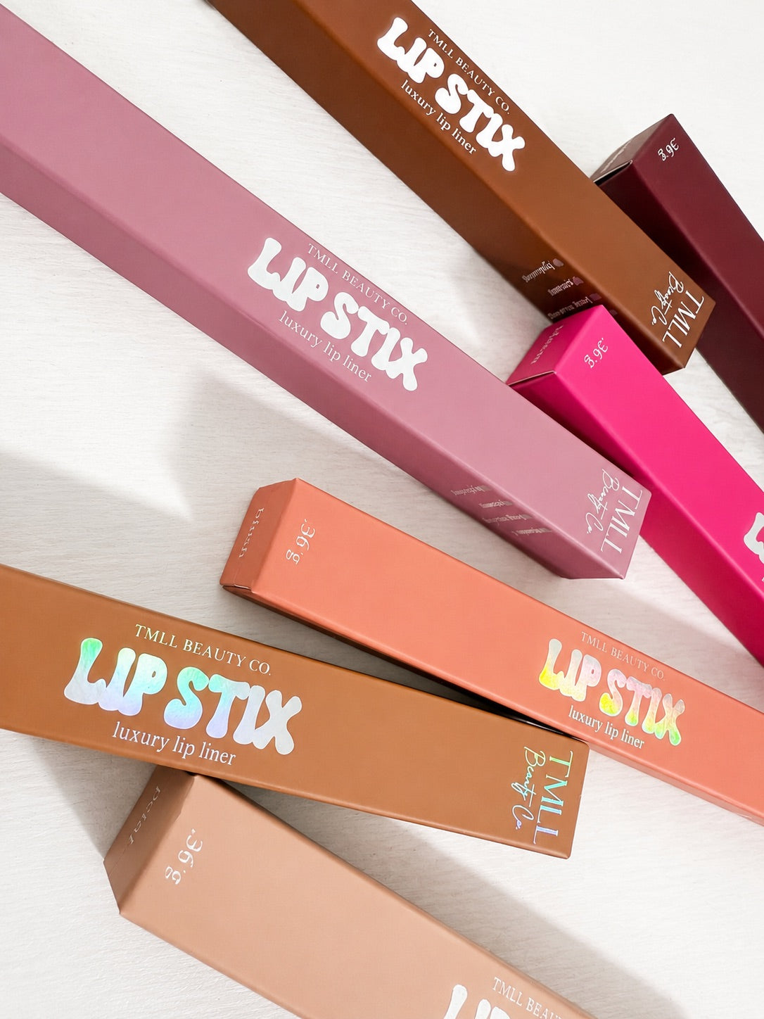 Assorted luxury lip liner boxes and pencils laid diagonally in pink and brown tones.