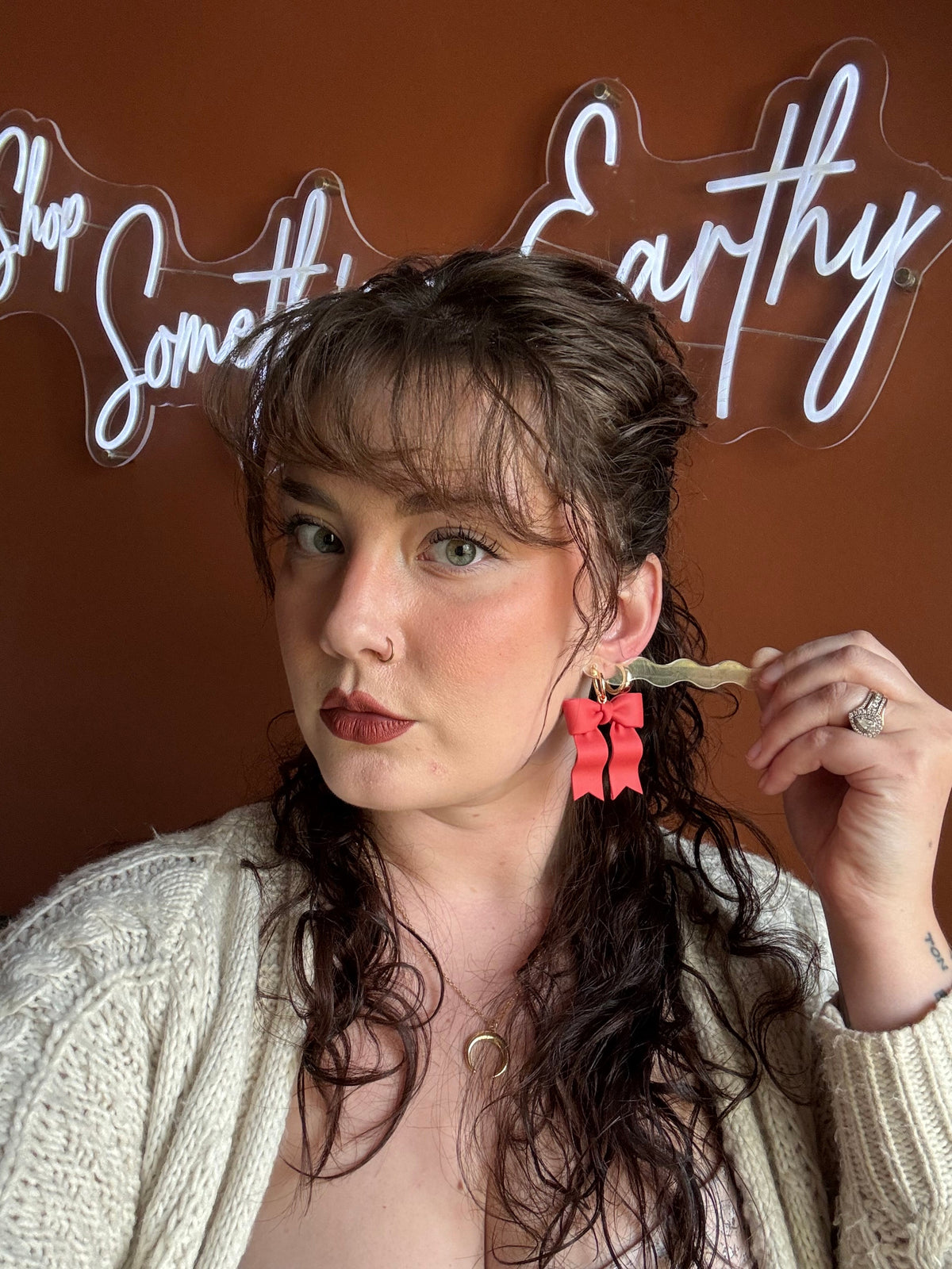 Red ribbon bow earrings with gold hoops worn with long hair