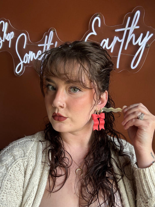 Red ribbon bow earrings with gold hoops worn with long hair