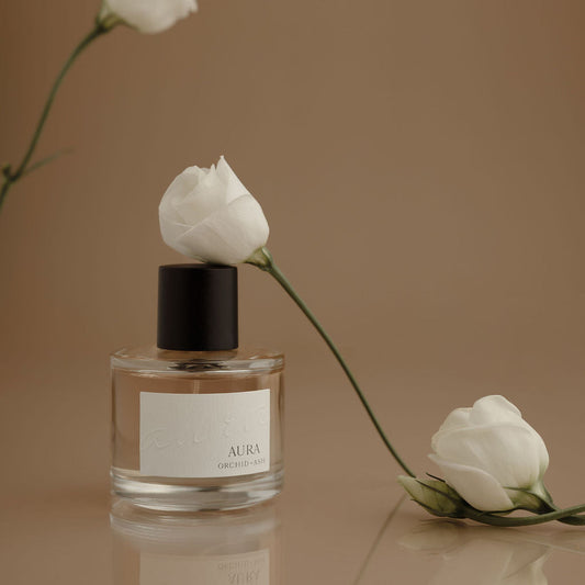 Perfume bottle with black cap and clear glass, featuring a floral label