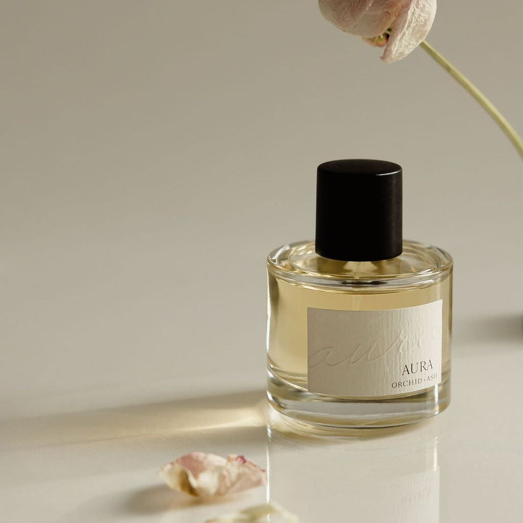 Perfume bottle with black cap, clear glass and floral label with rose accents