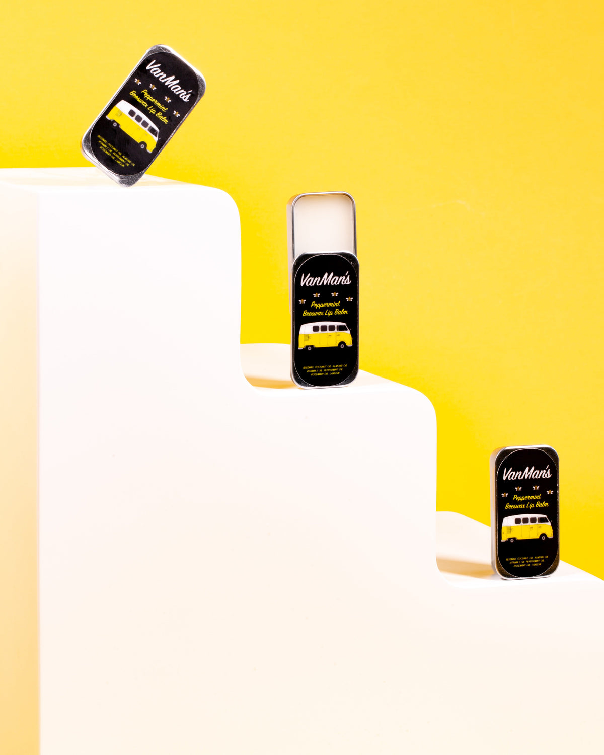 Peppermint beeswax lip balm tin display with black tins on a white surface