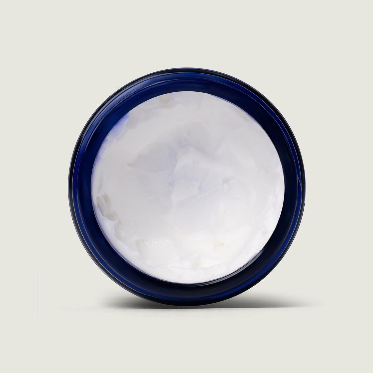 Top view of white whipped balm inside a blue-lidded jar