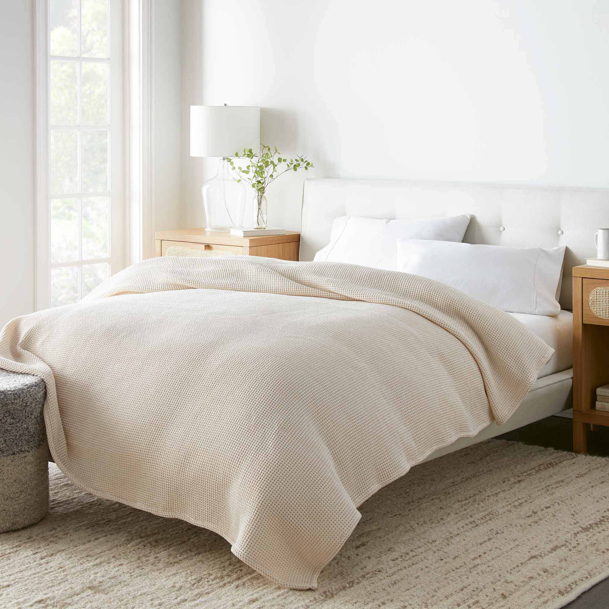 Natural waffle-knit blanket draped over bed, textured grid surface visible.
