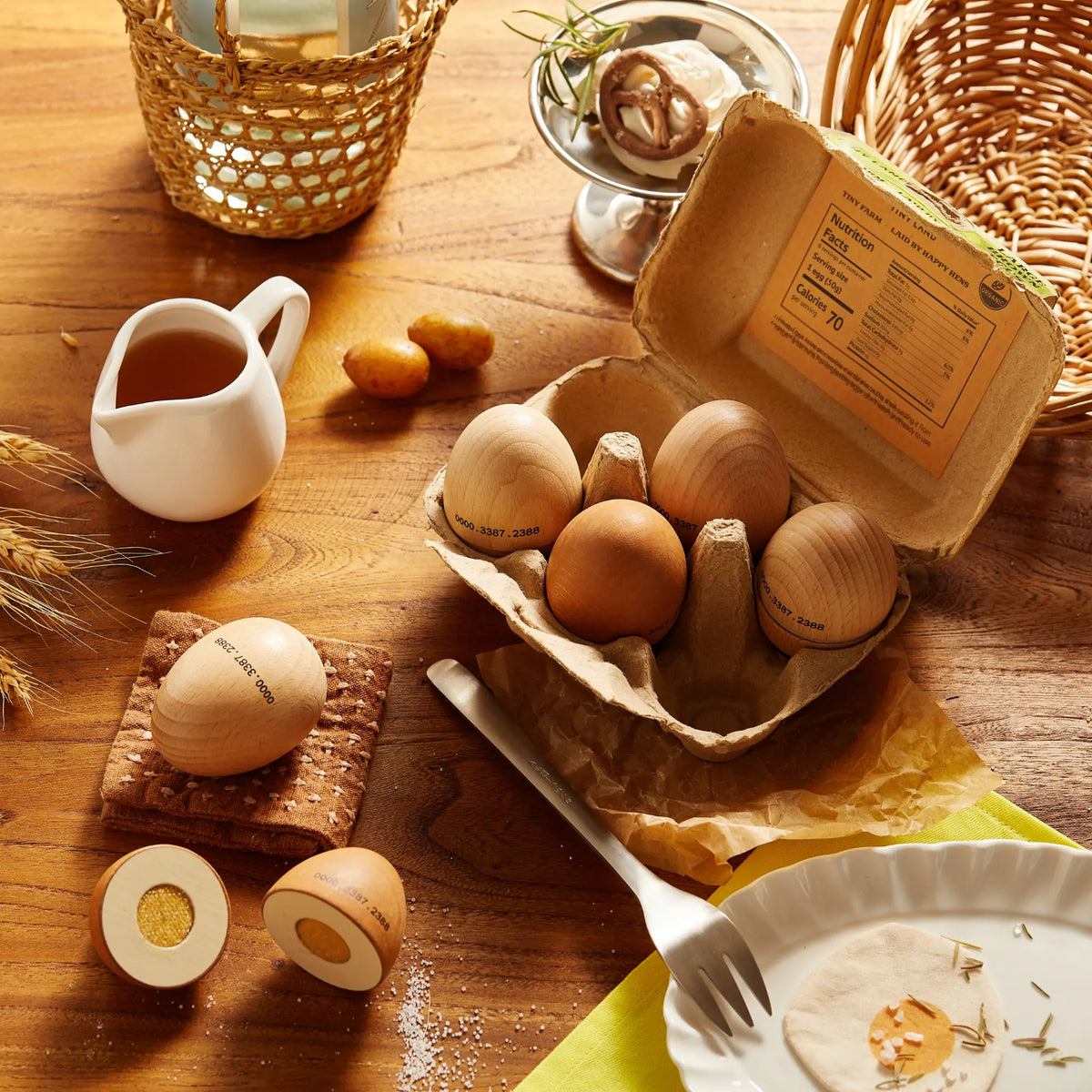 Wooden play eggs and fried egg pieces arranged in an open carton with a wooden egg cup.