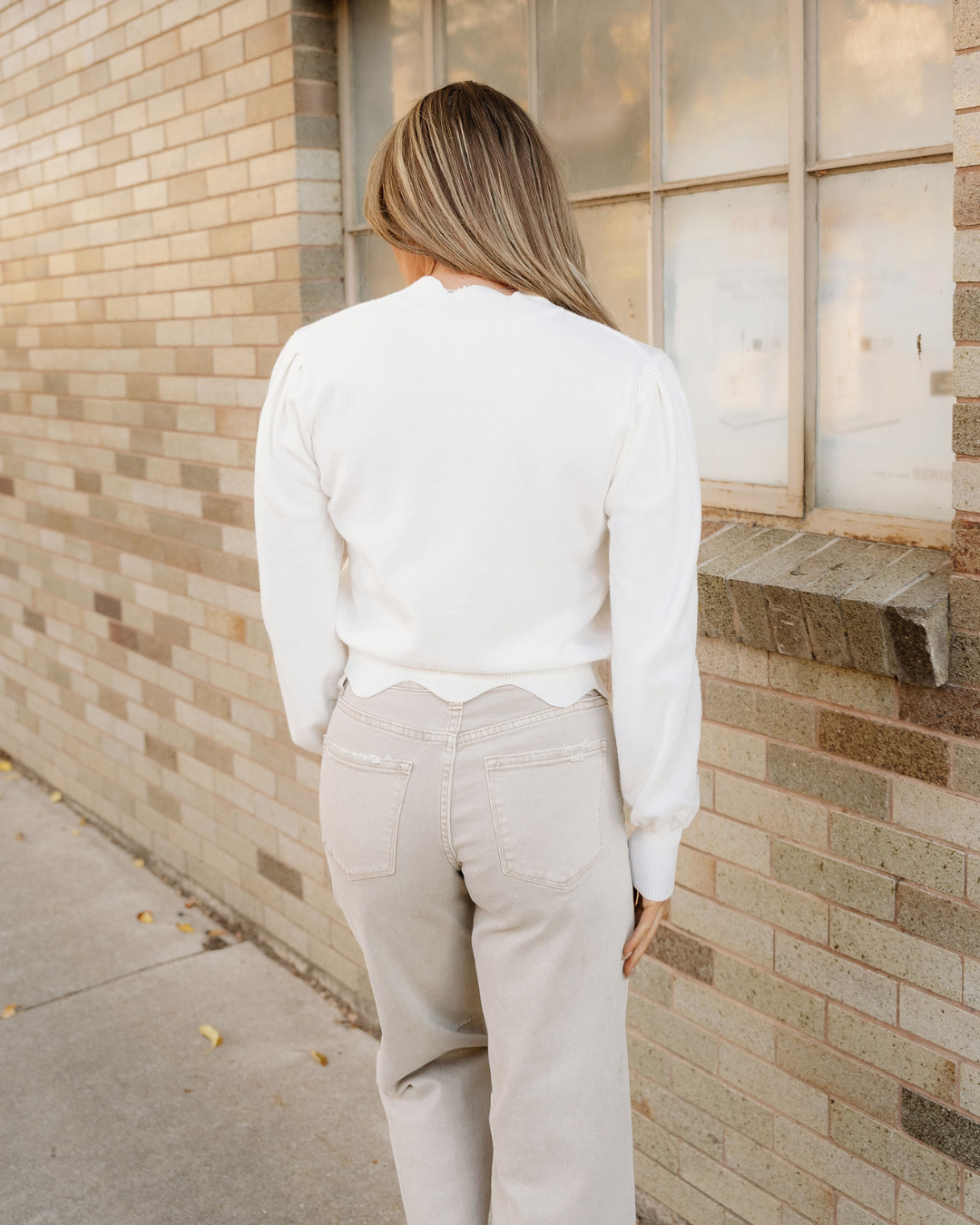 Back view of white cropped sweater with long sleeves and clean hem