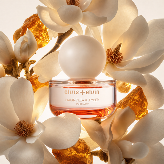 Eau de parfum jar with amber liquid surrounded by white magnolia flowers