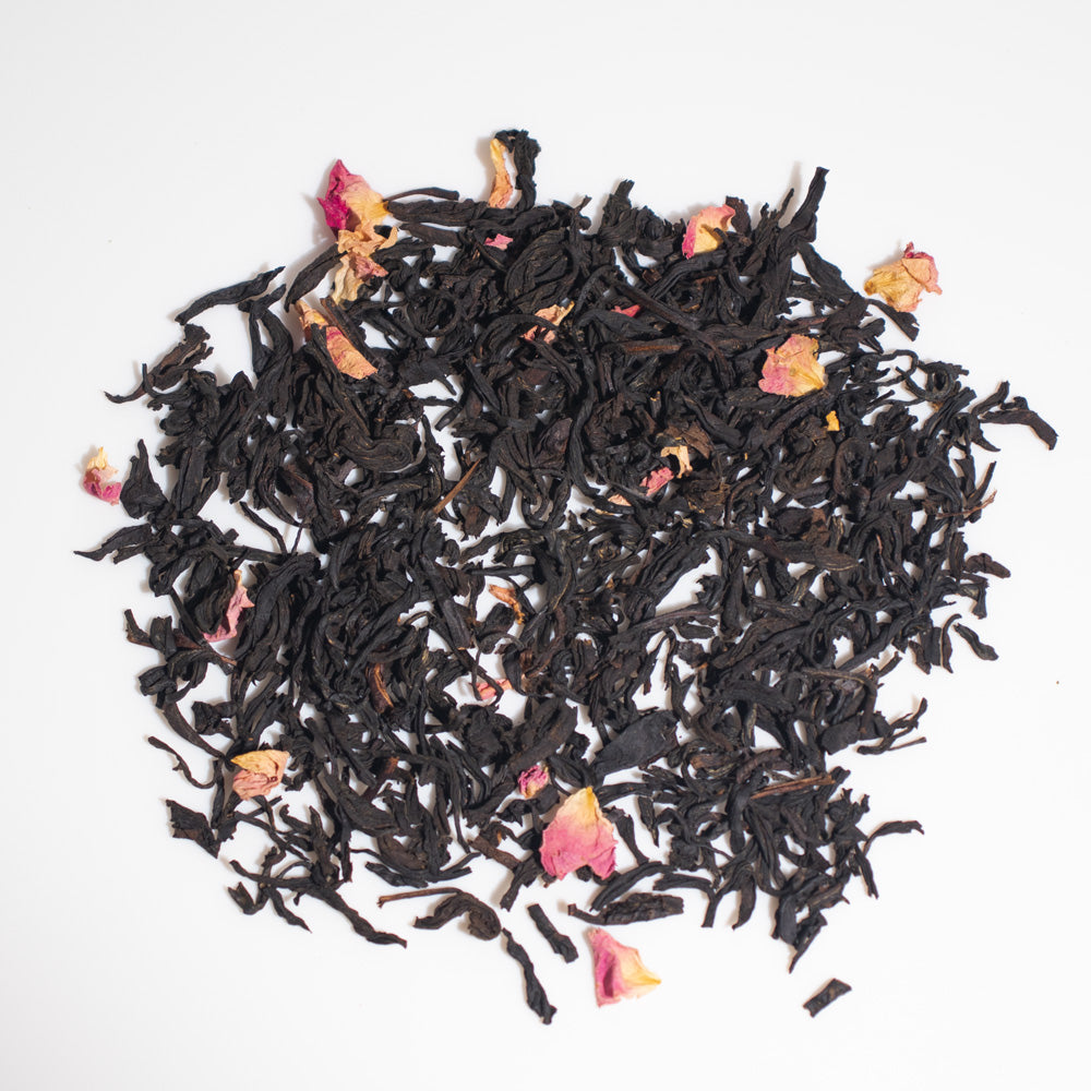 Pile of loose black tea leaves with small rose petals mixed in