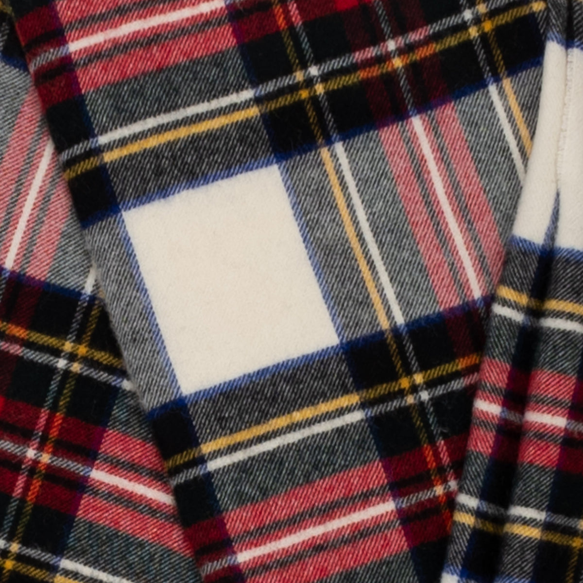 Close-up of plaid fabric: cream squares with red, navy, gray, and yellow tartan lines