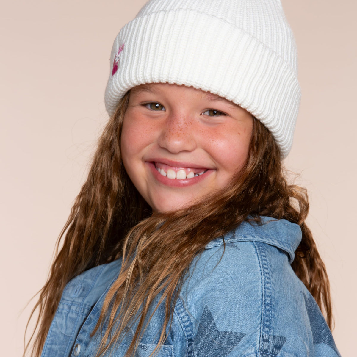 White rib-knit beanie with a fox patch, worn on a child