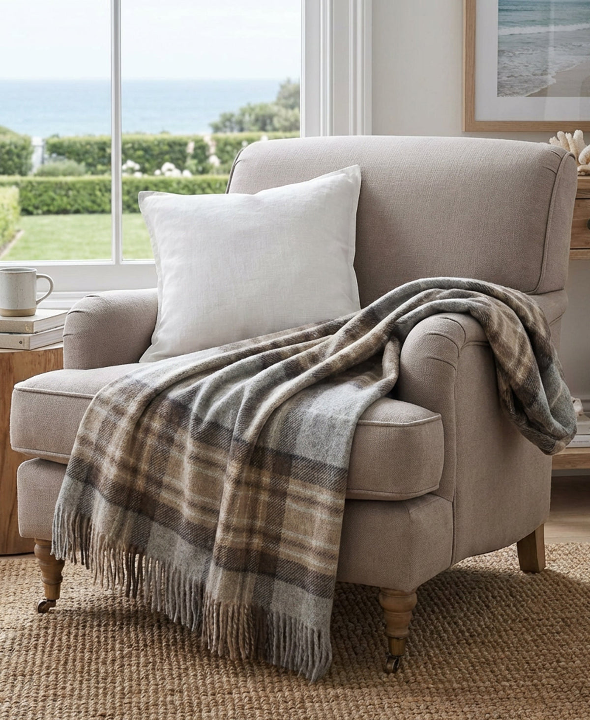 Plaid wool throw blanket draped on beige armchair, gray and tan tones, fringed edge