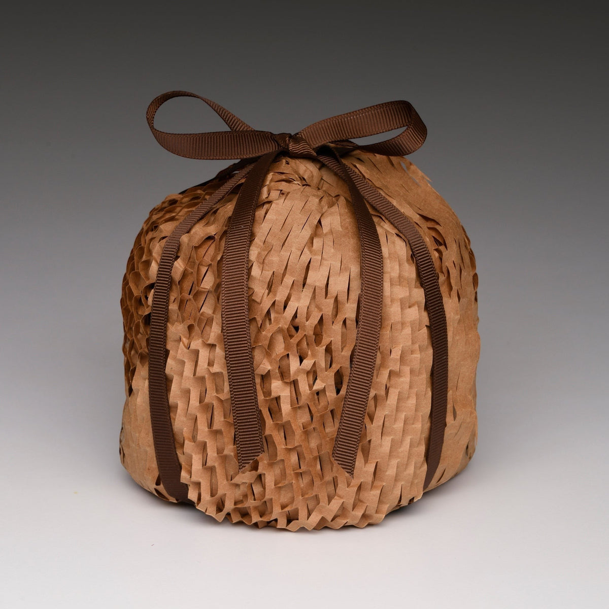 Packaged soy candle in woven-look kraft wrap with dark brown ribbon bow