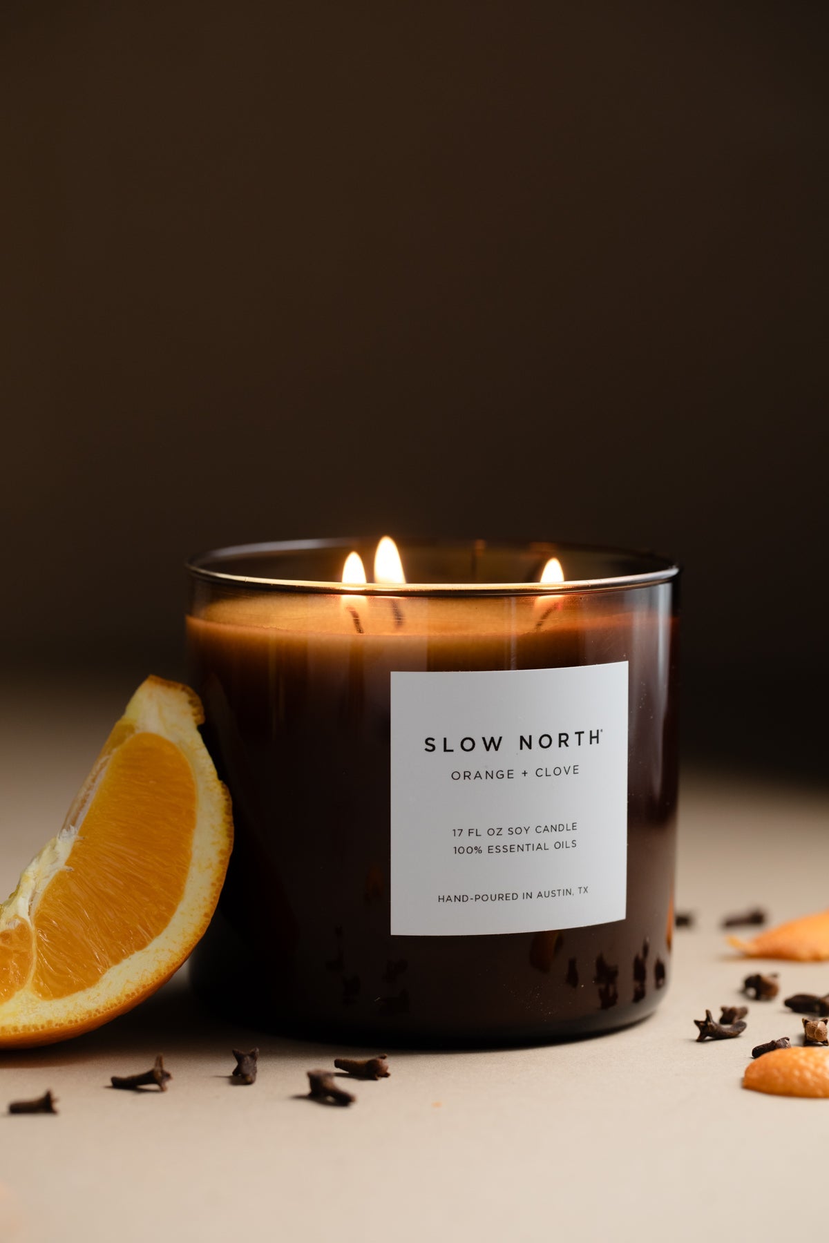 Slow North 3-wick candle, amber wax in glass container, with three burning wicks