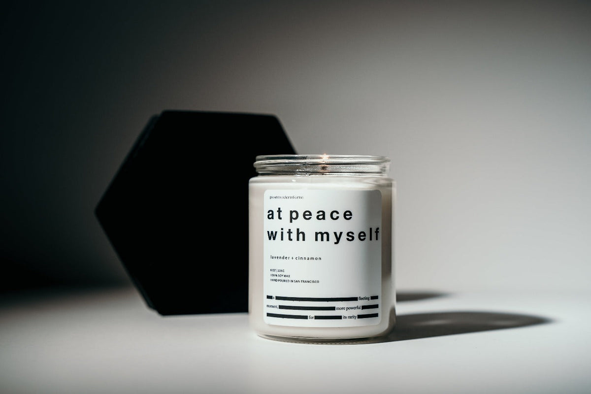 Scented jar candle with black lid and white label, lavender and cinnamon scent.