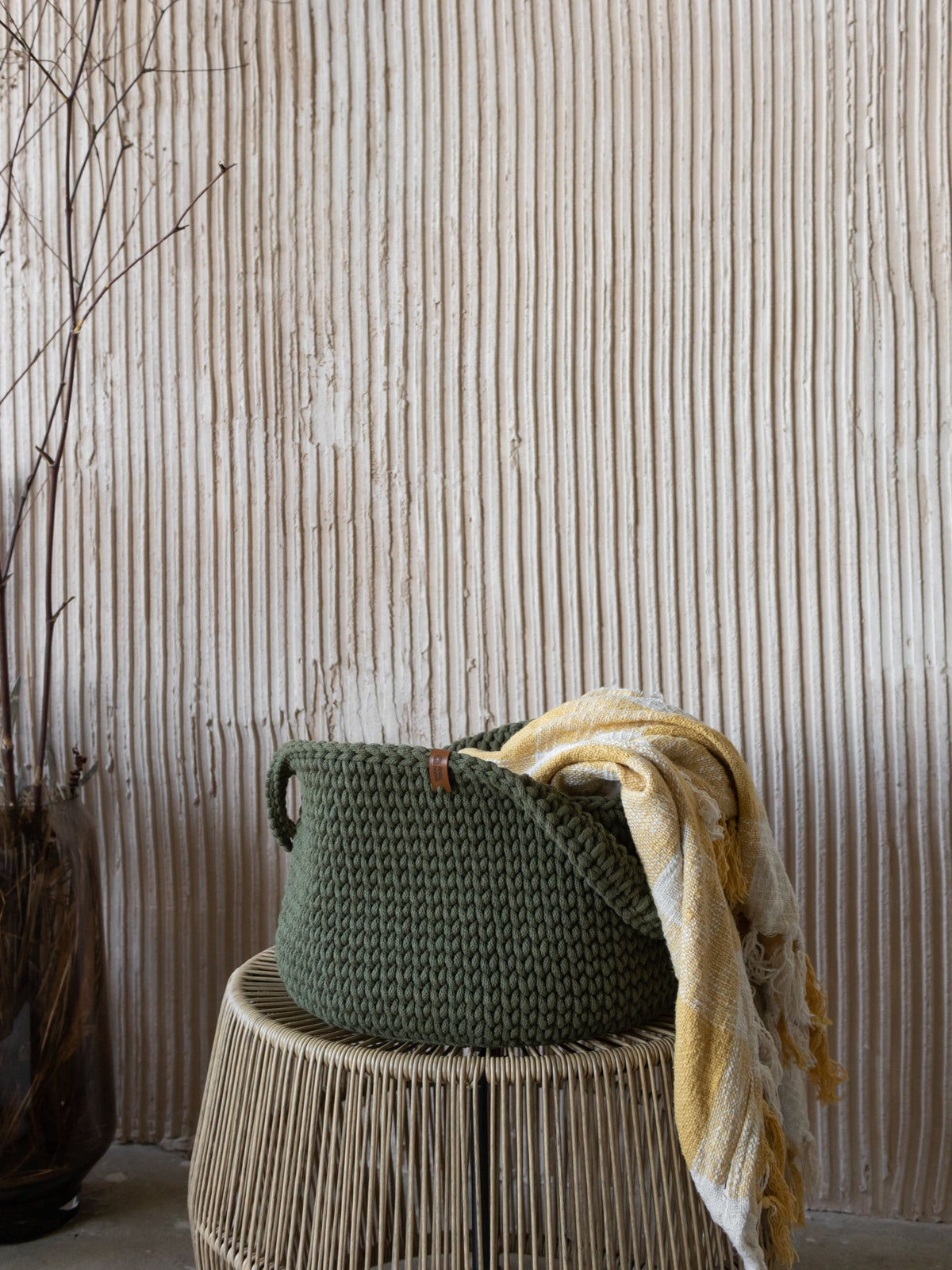 Round woven basket with handles, olive-green with woven carry handles.
