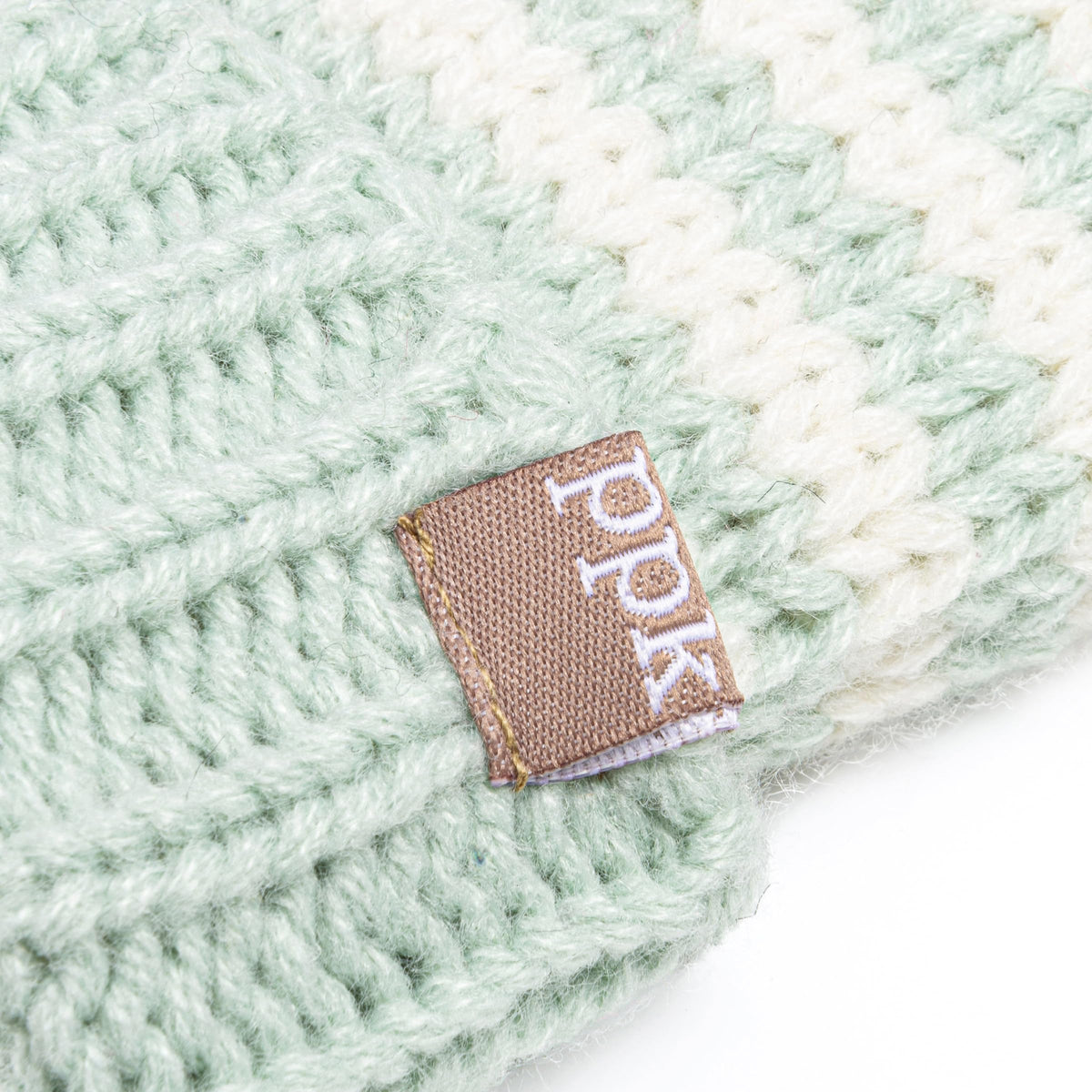 Mint green knit hat detail with small fabric logo tag