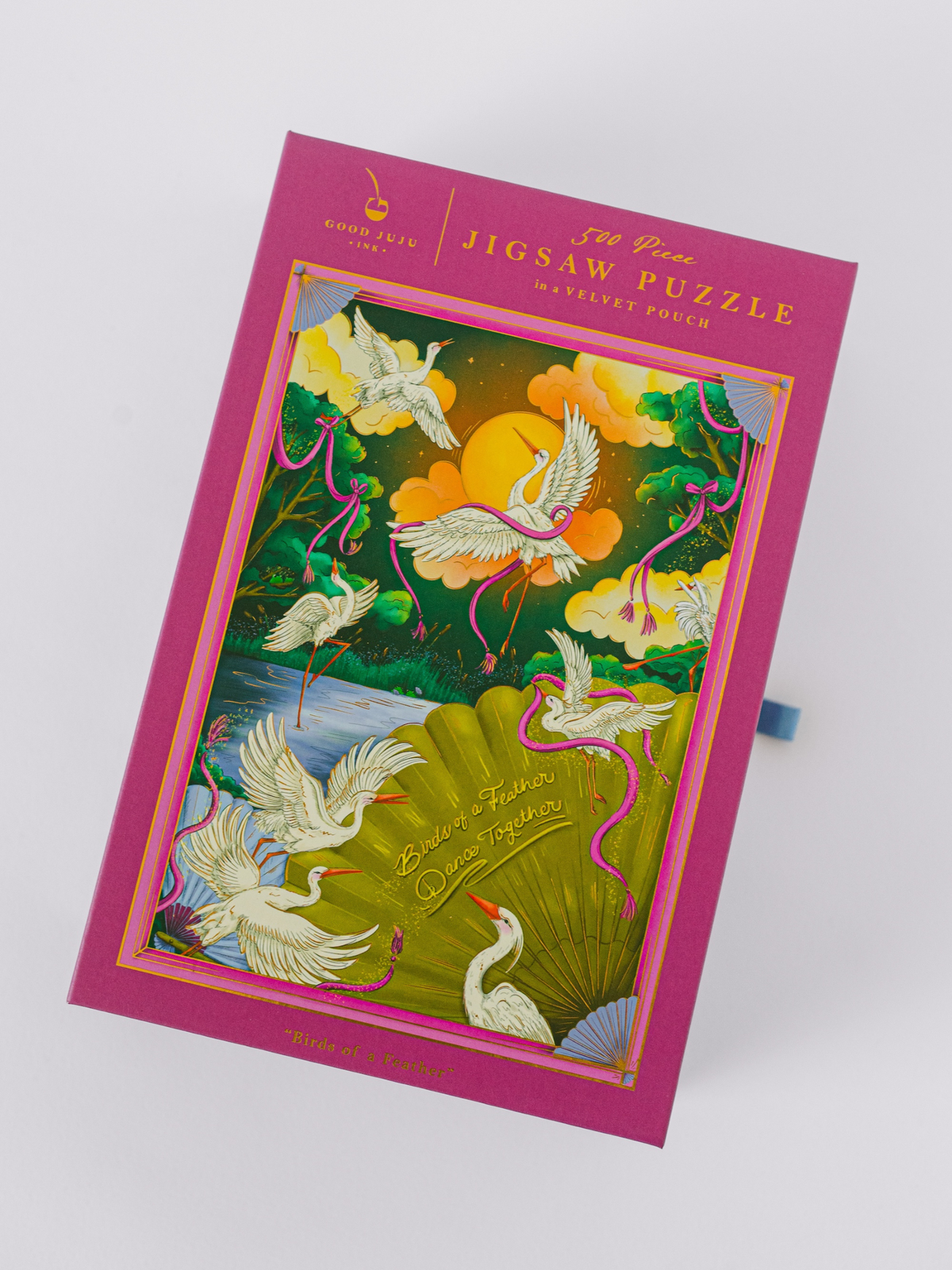 Jigsaw puzzle box front with birds in flight, pink border, and gold title text