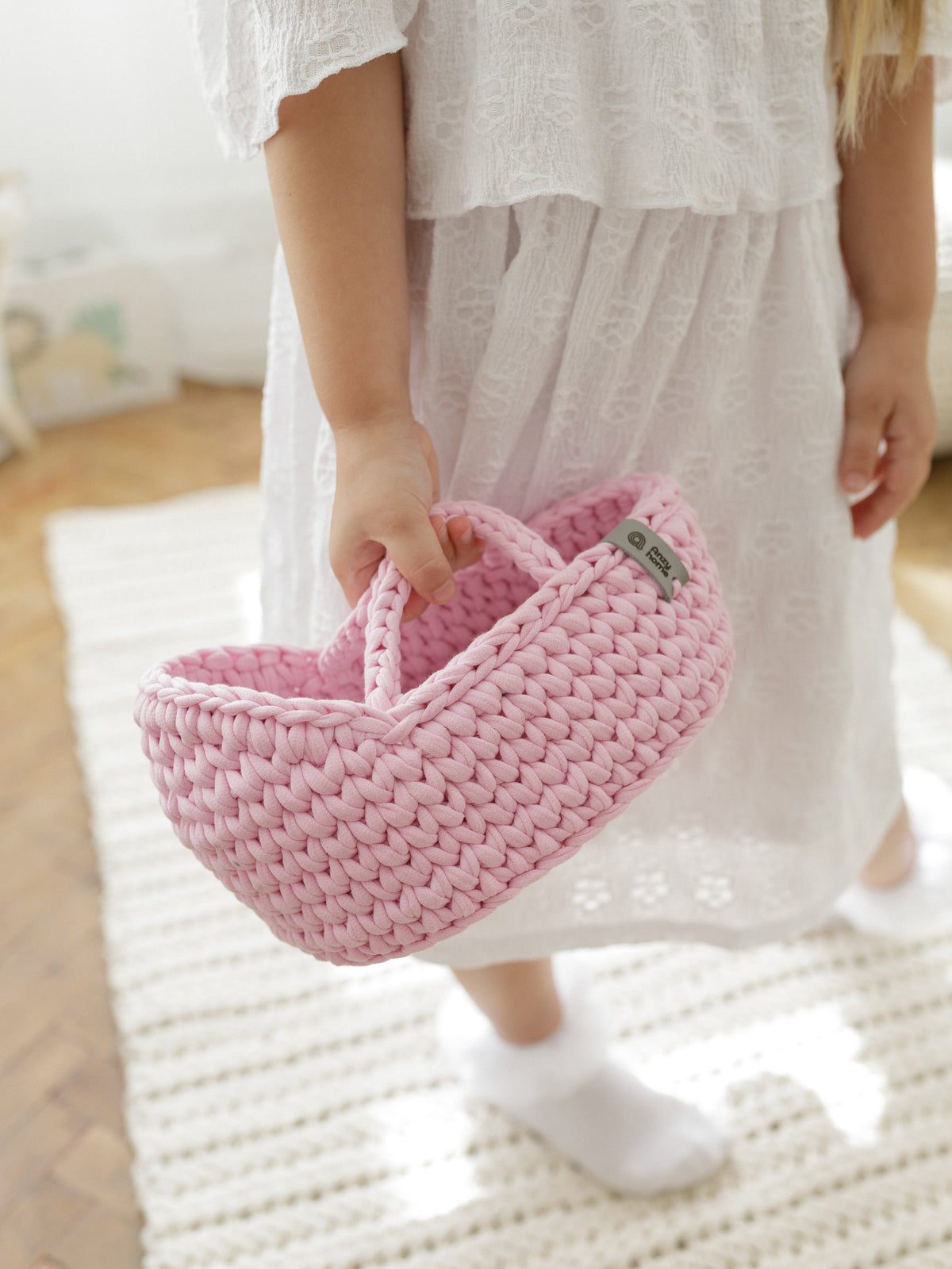 Pink crocheted mini doll moses basket held by a child with fabric lining inside