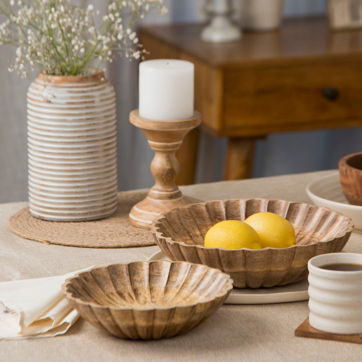 Natural scalloped wooden bowl holding lemons, with a smaller matching bowl