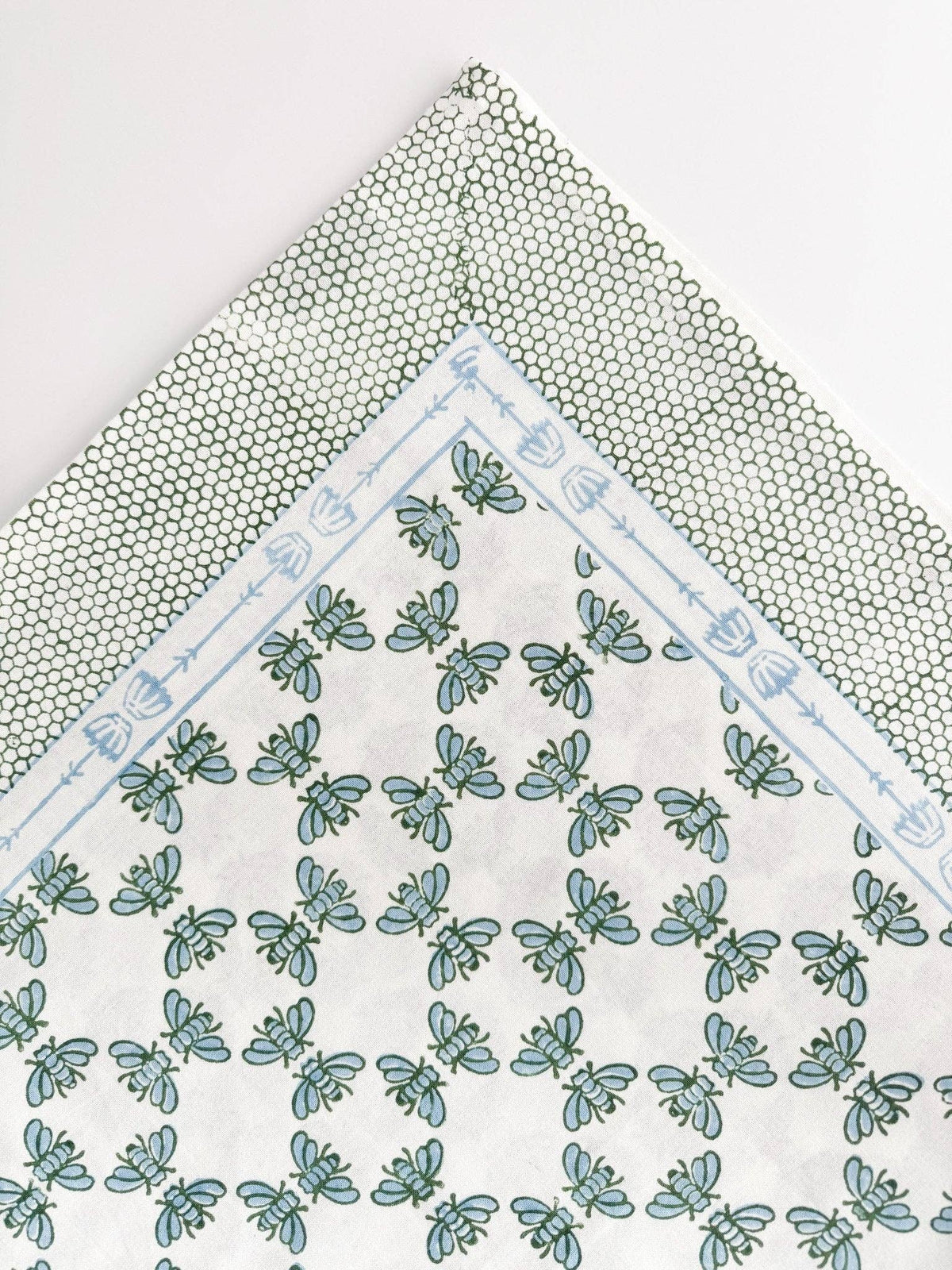Table throw corner view with blue-and-sage floral circle pattern and light blue framed border.