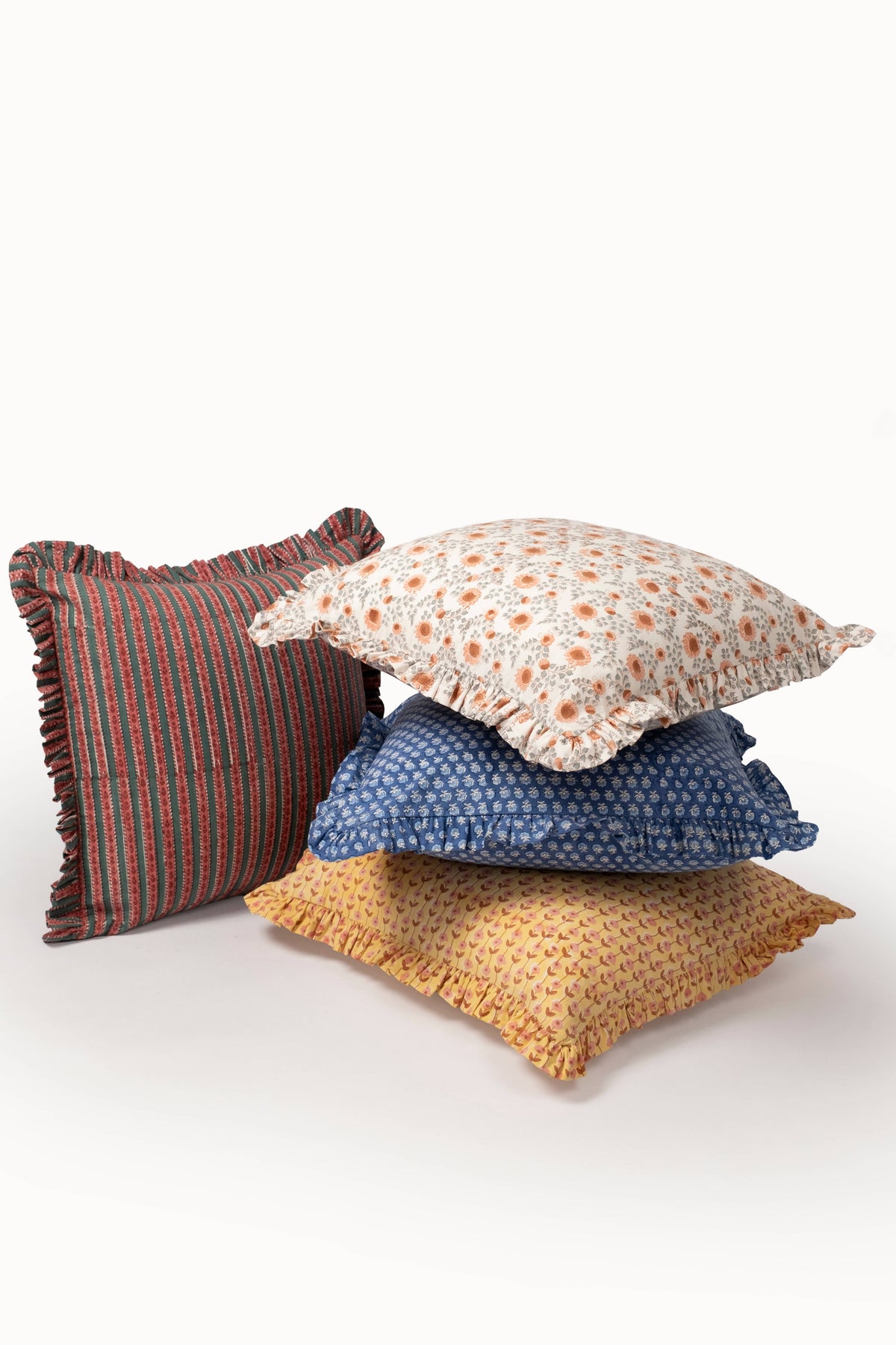 Ruffle-edged pillow covers with striped crimson and blue and a cream speckled print
