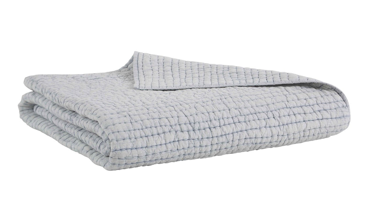 Stone-washed cotton quilt folded, light gray with textured weave and stitched lines.