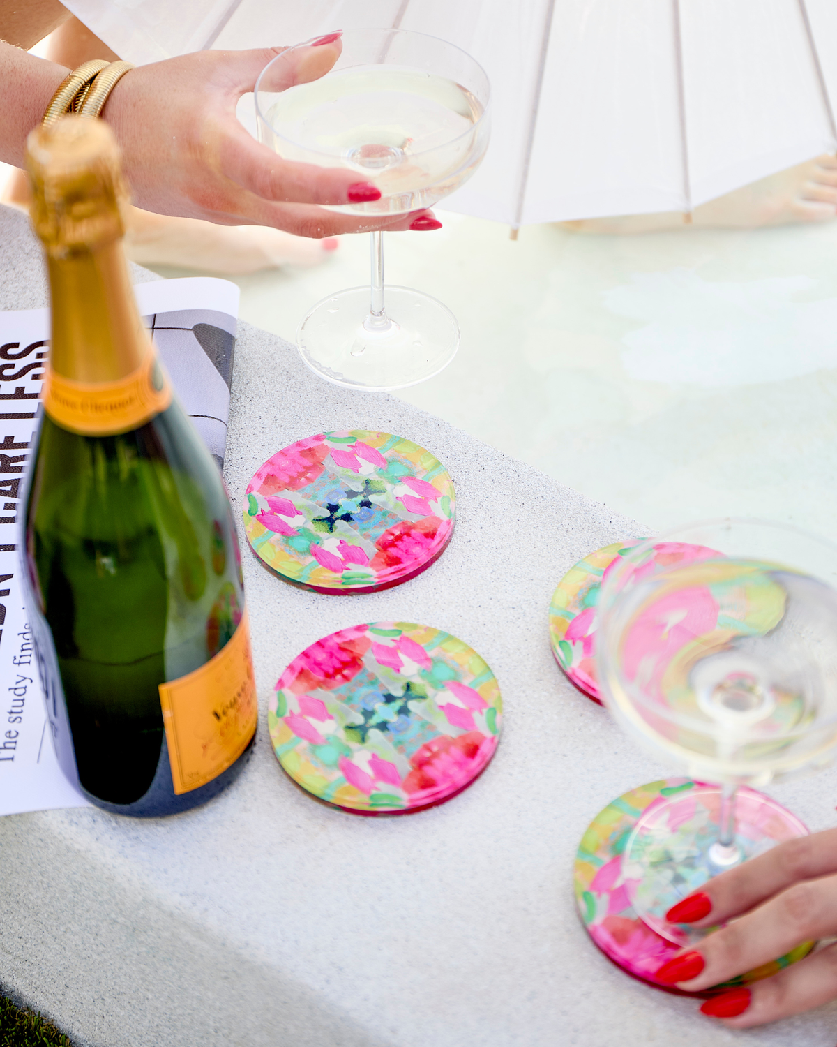 Set of round acrylic drink coasters with colorful floral confetti pattern in pink and green