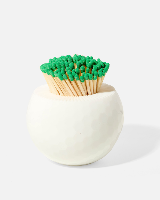 White faceted match holder with green-tipped wooden match heads
