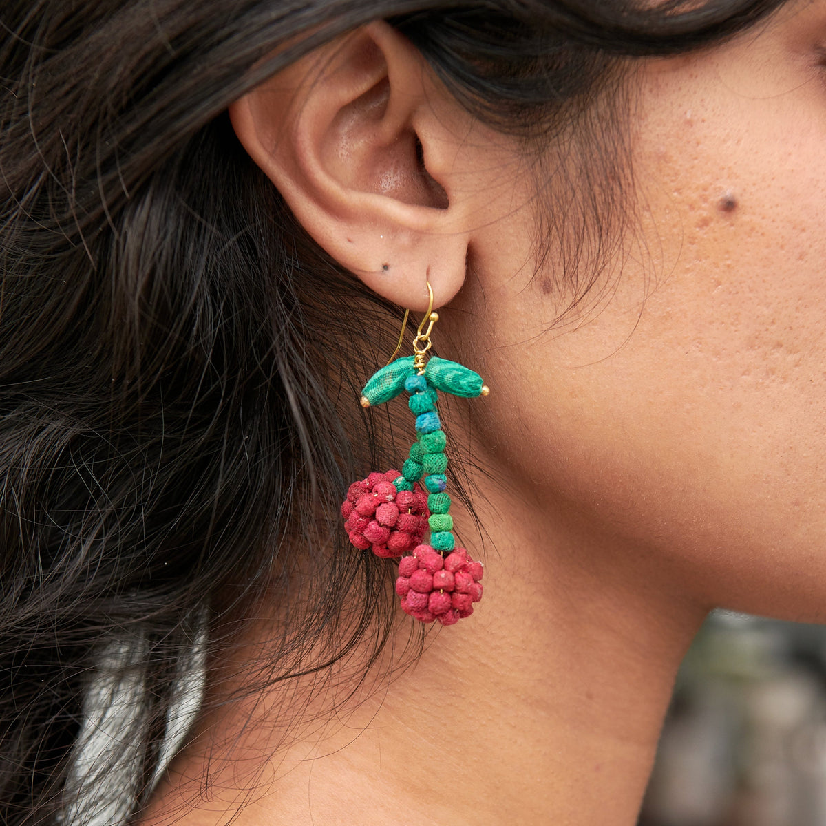Teal and red beaded drop earrings with gold hooks and red berry pom-pom clusters.