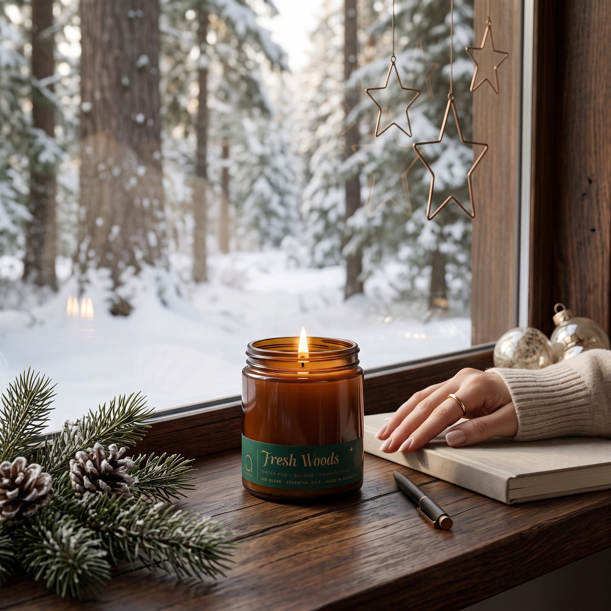 Amber glass Fresh Woods candle jar with green label and two lit wicks on tabletop