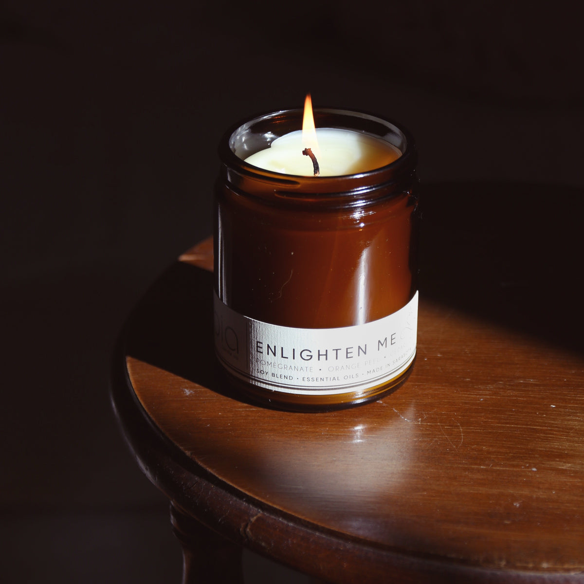 Amber glass jar soy candle with flame and white ENLIGHTEN ME label