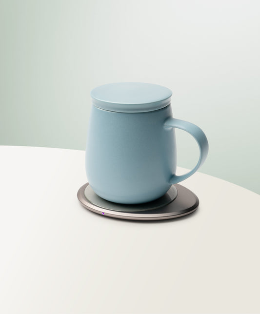 Moonmist blue mug on round dark warming base, smooth rim and carry handle