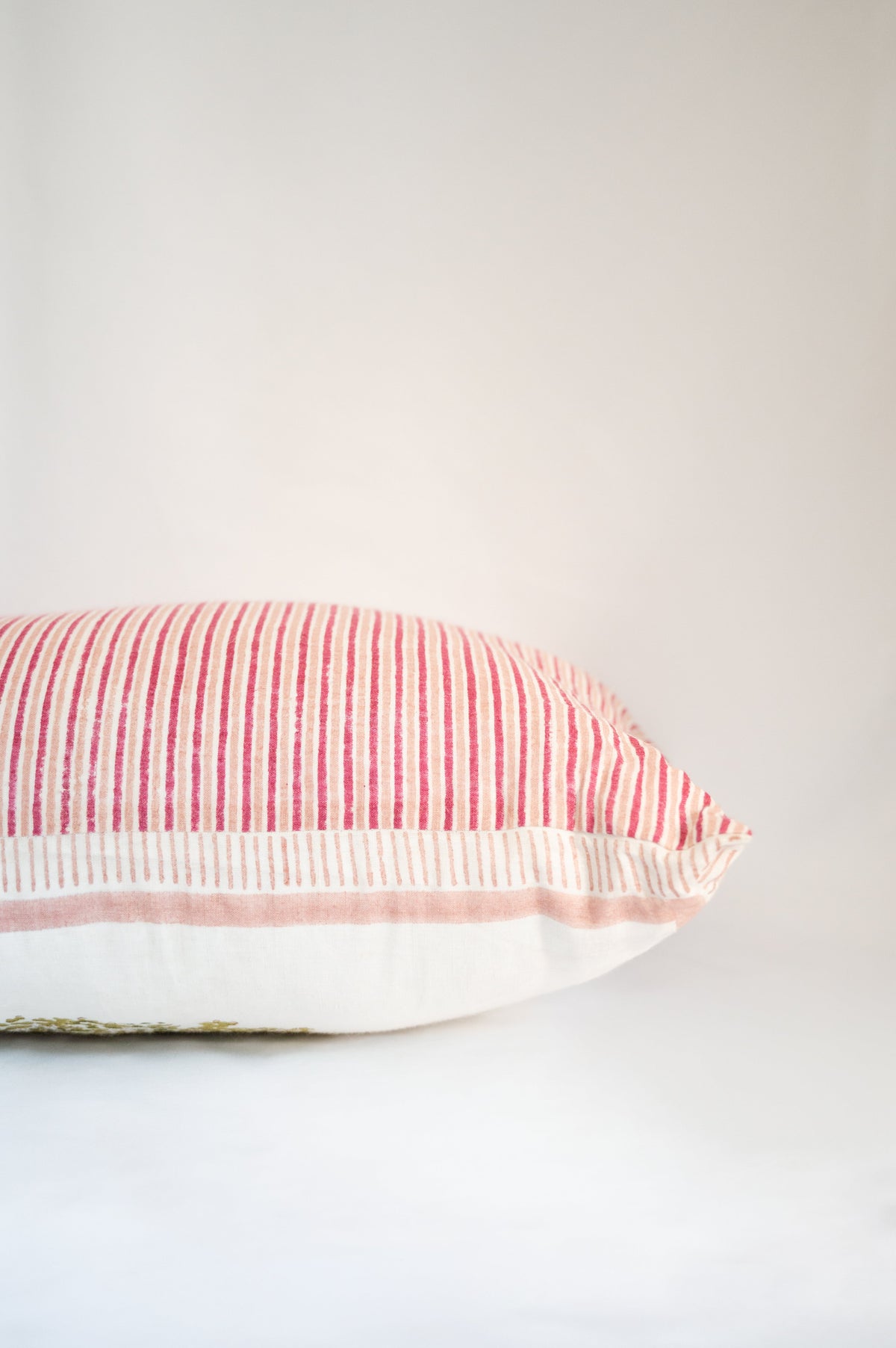 Block print cushion with striped side panel and pink-and-white edge trim detail