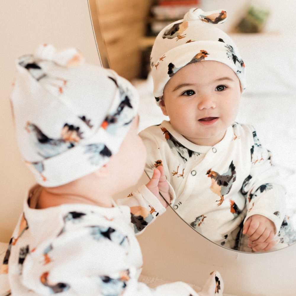 Toddler wearing a light gray knotted beanie with sheep print and ribbed cuff