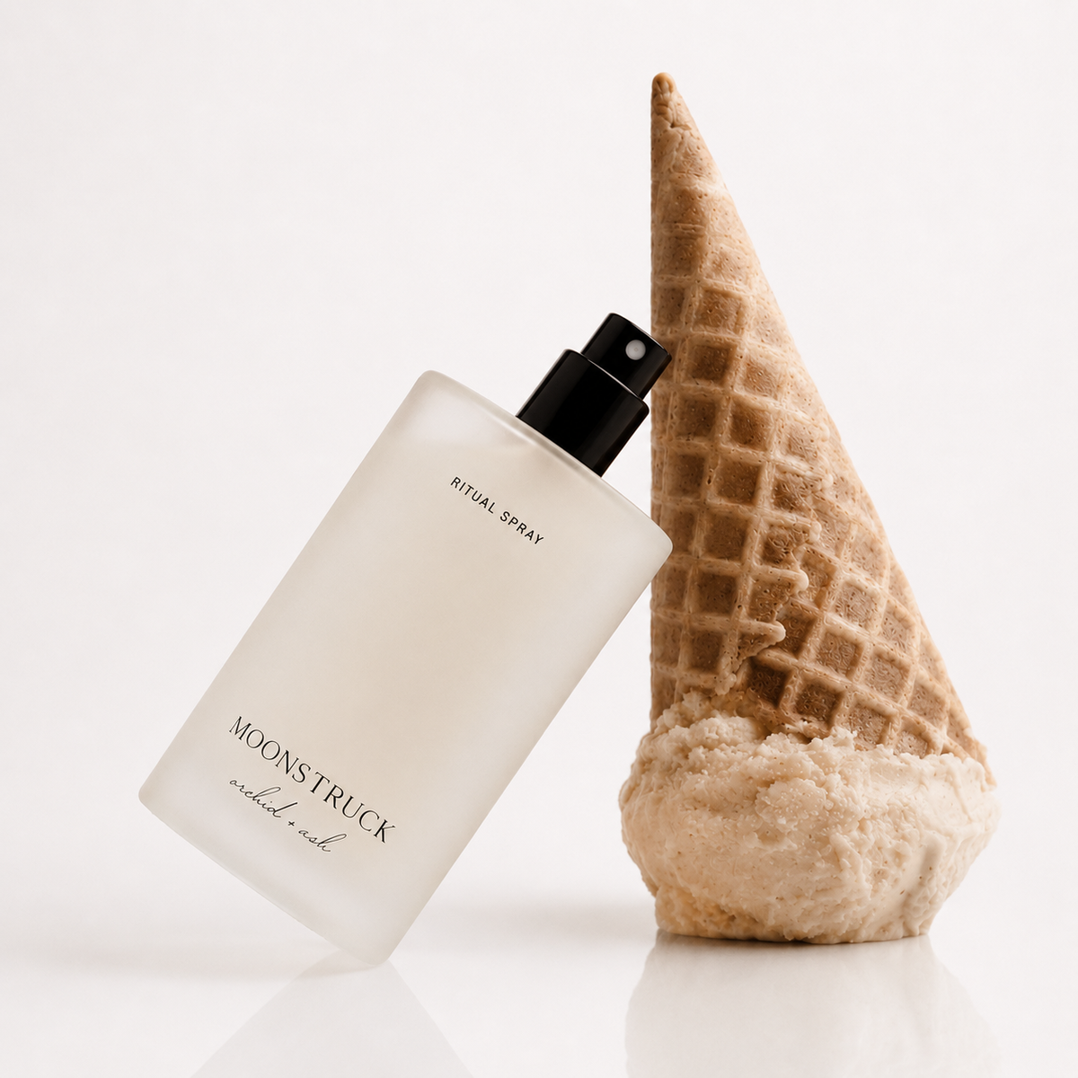 MOONSTRUCK ritual spray bottle with black nozzle, beside vanilla pod and waffle cone