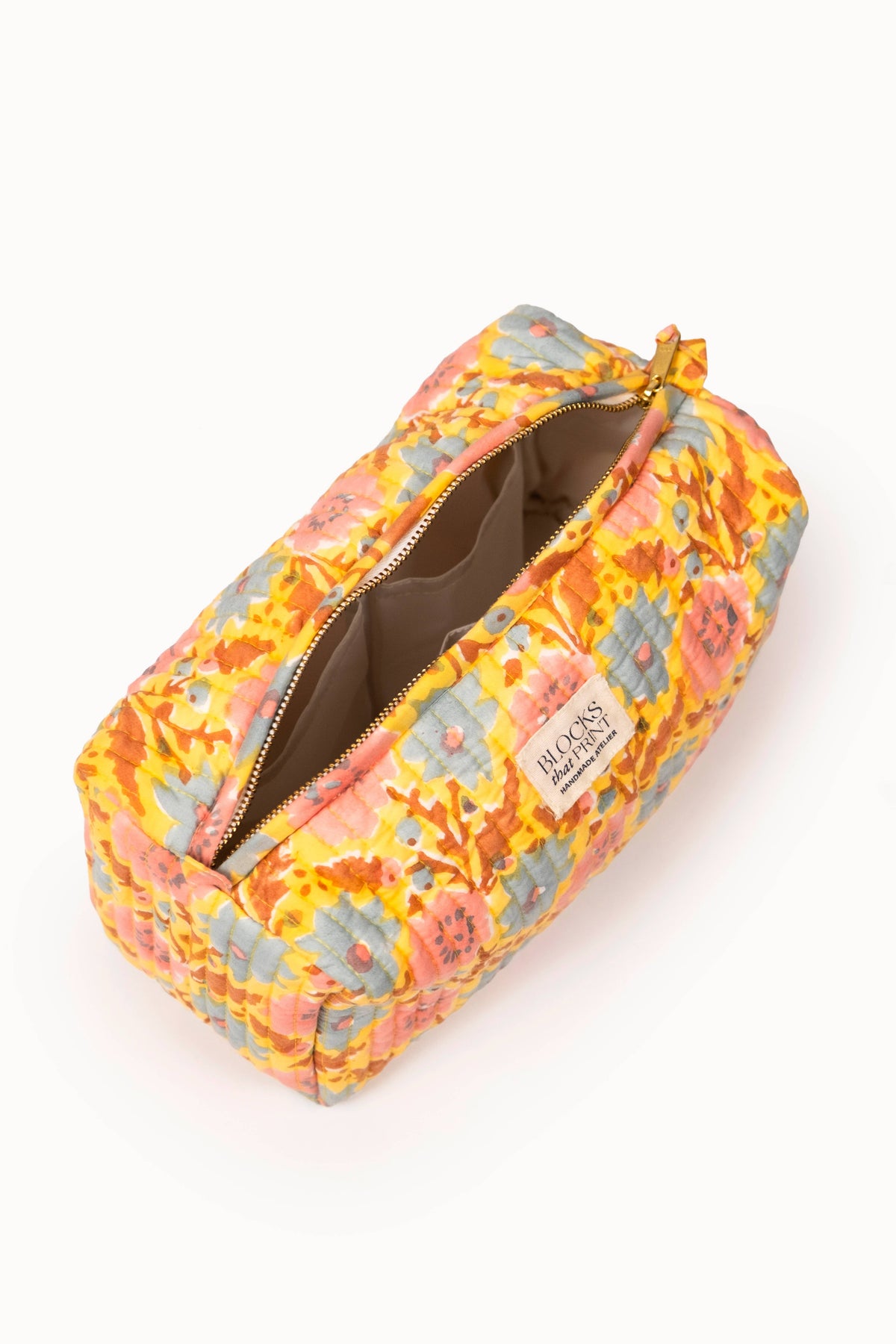 Quilted travel pouch with open top, patterned interior and drawstring tie